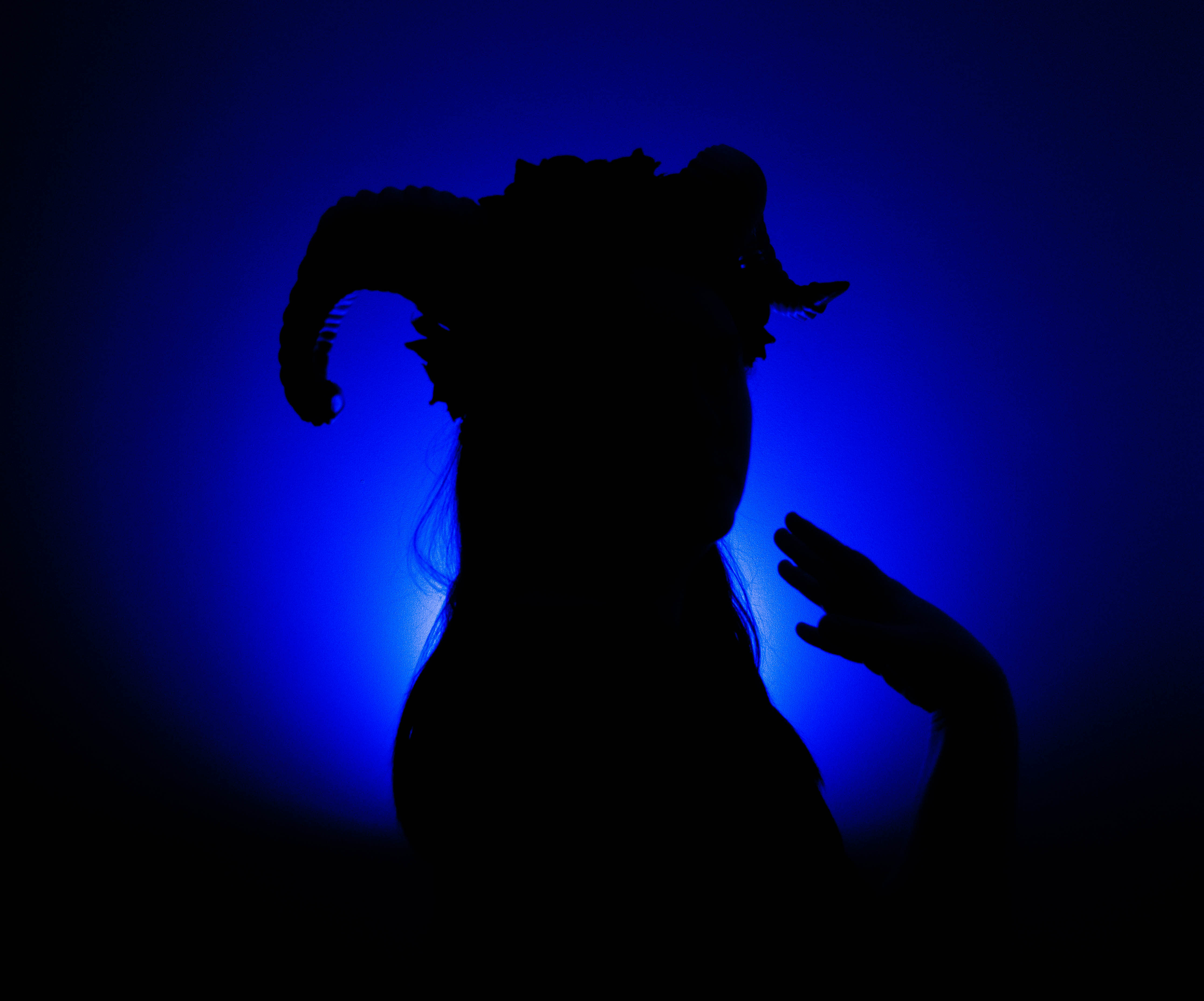 Shadow with horns against a blue light background.