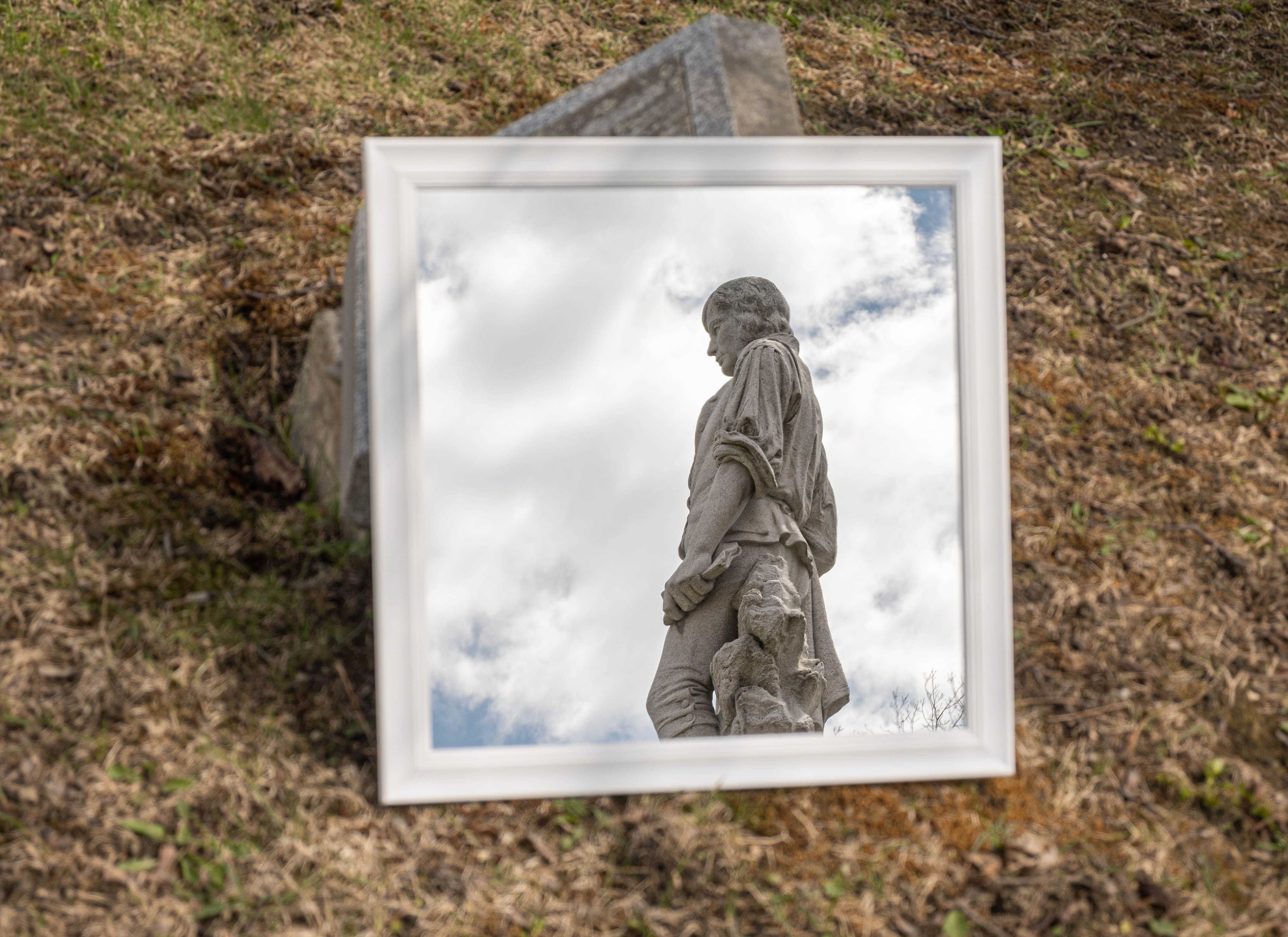 Reflection of a granite statue in a mirror on the ground.